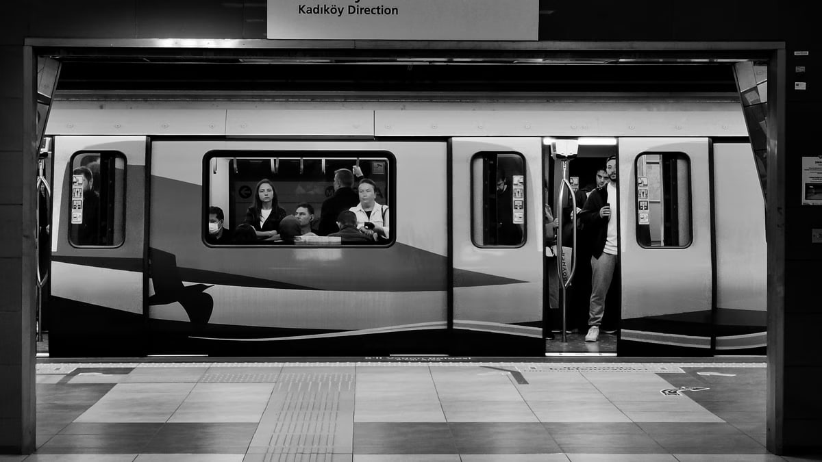 Passengers wait inside a subway train at Kadıköy station in black and white.